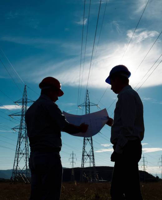 silhouette of two engineers standing at electricity station, discussing plan